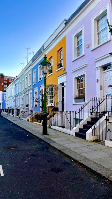 A row of vibrant, pastel-colored terraced houses along a quiet street on Lillie Road to Talgarth Road, featuring painted facades in shades of blue, yellow, and lilac. The exteriors include white-frame